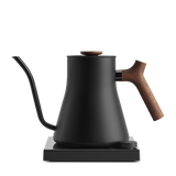 Matte black electric kettle with a slender gooseneck spout and a wooden handle and lid knob on a square base.