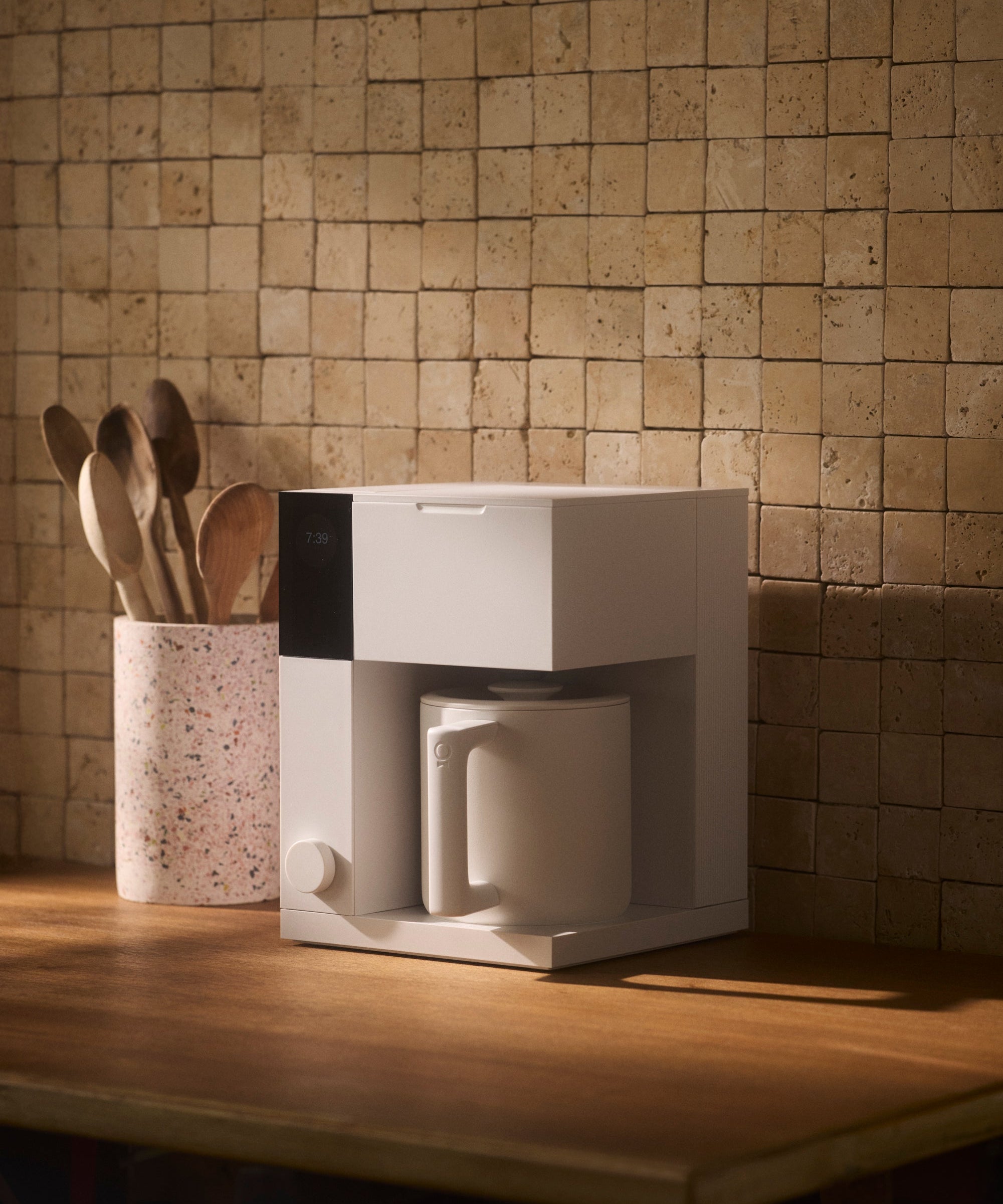 Compact white coffee maker with a modern rectangular design and integrated cup on a wooden countertop.