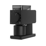 Matte black rectangular coffee grinder with large adjustment dial and clear bean hopper on top.