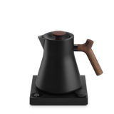 Matte black electric kettle with wooden handle and lid knob, sitting on a black base with digital display.