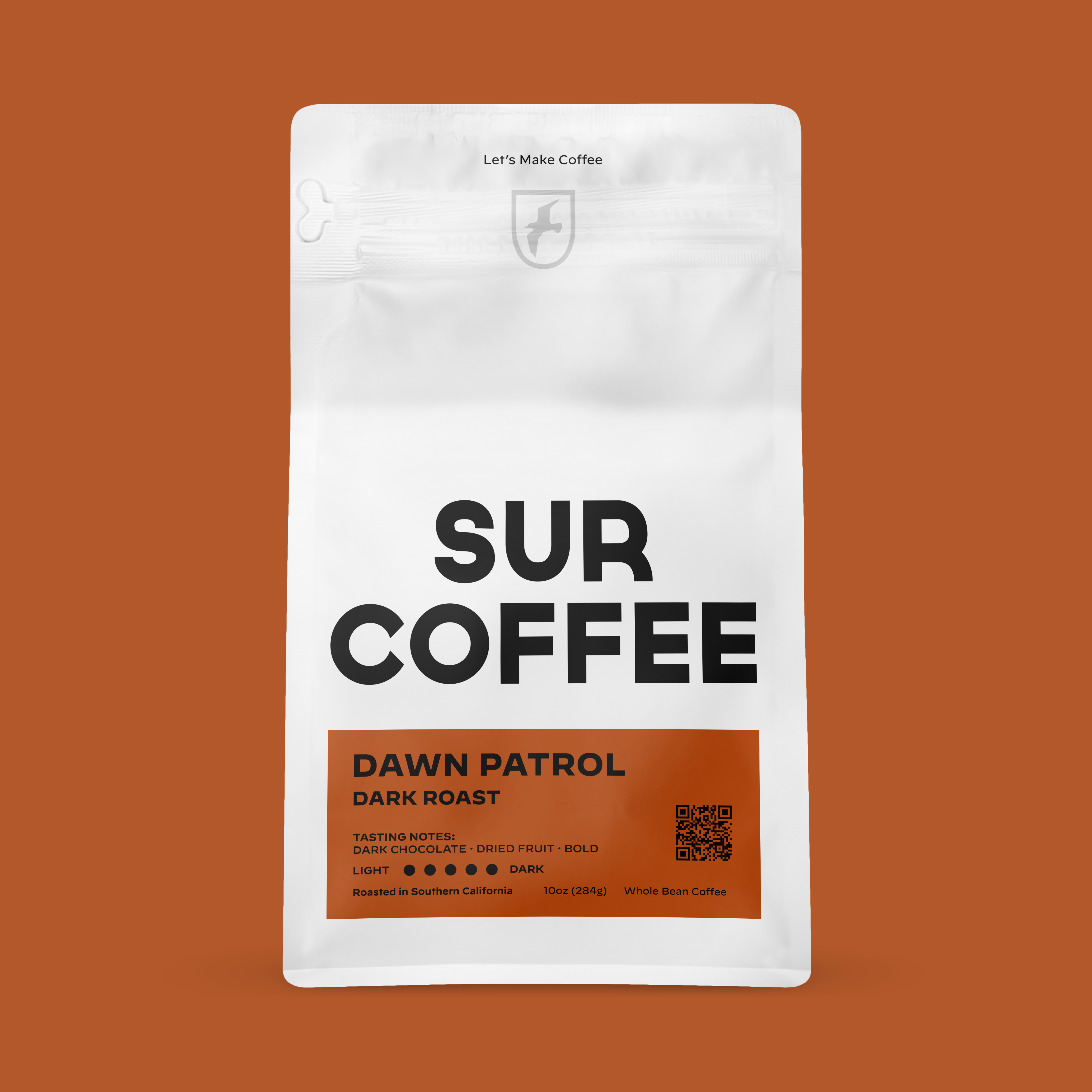 White matte bag with SUR COFFEE logo and orange label reading Dawn Patrol Dark Roast with tasting notes, roast level, and QR .