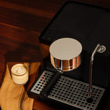 Matte black espresso machine with silver accents, steam wand, and drip tray on wooden surface with latte and cloth nearby.