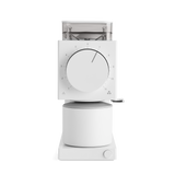 Matte white coffee grinder with large central dial, clear bean hopper, and cylindrical catch container.