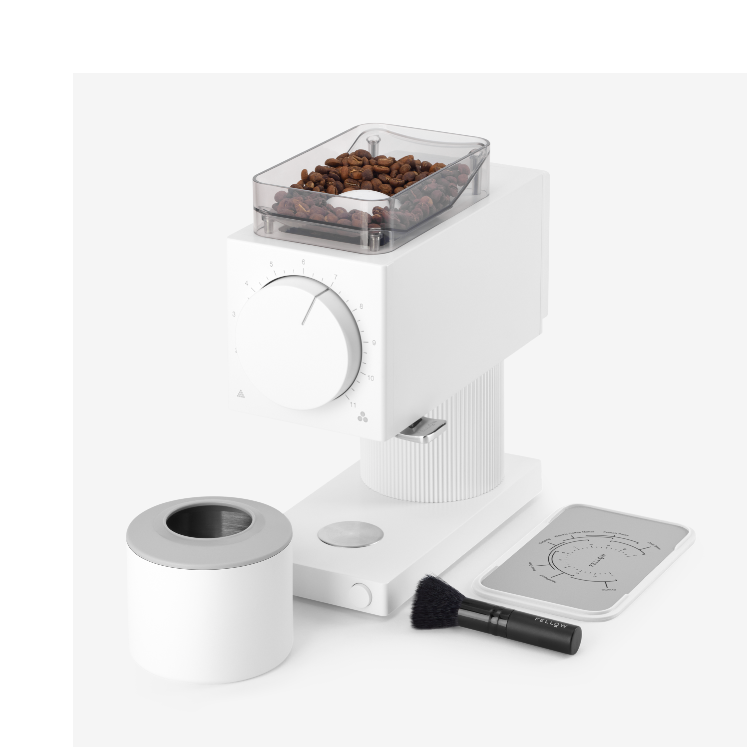 Matte white compact coffee grinder with clear bean hopper, large front dial, detachable grounds container, cleaning brush,.