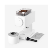 Matte white compact coffee grinder with clear bean hopper, large front dial, detachable grounds container, cleaning brush,.