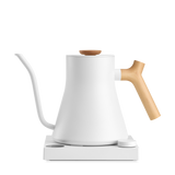 White matte electric kettle with long curved spout and natural wood handle and lid knob on a white base.