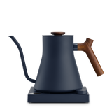 Matte navy blue electric kettle with a slim gooseneck spout, wooden handle and lid knob on black base.