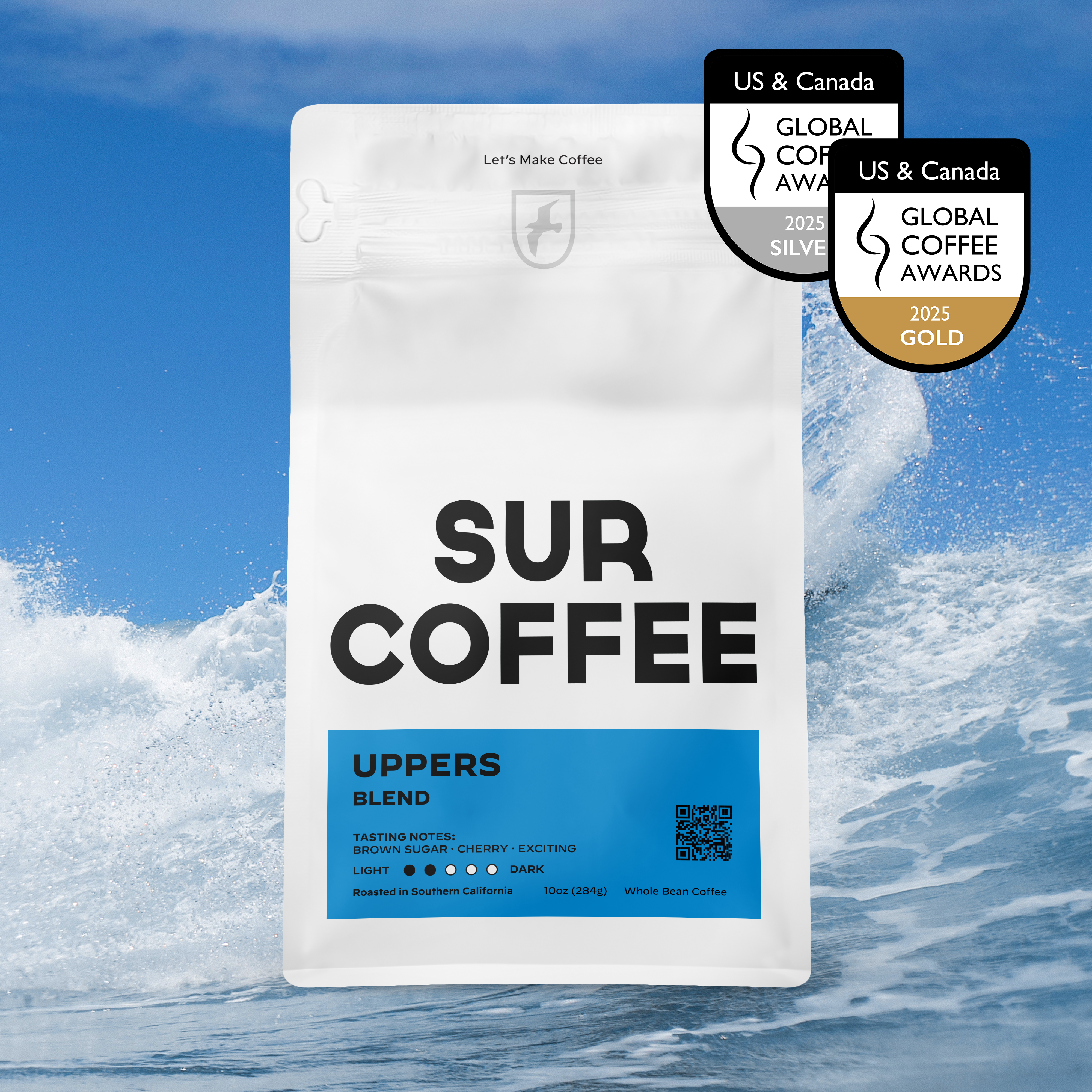 White matte coffee bag with black Sur Coffee logo and blue Uppers Blend label against ocean wave background.