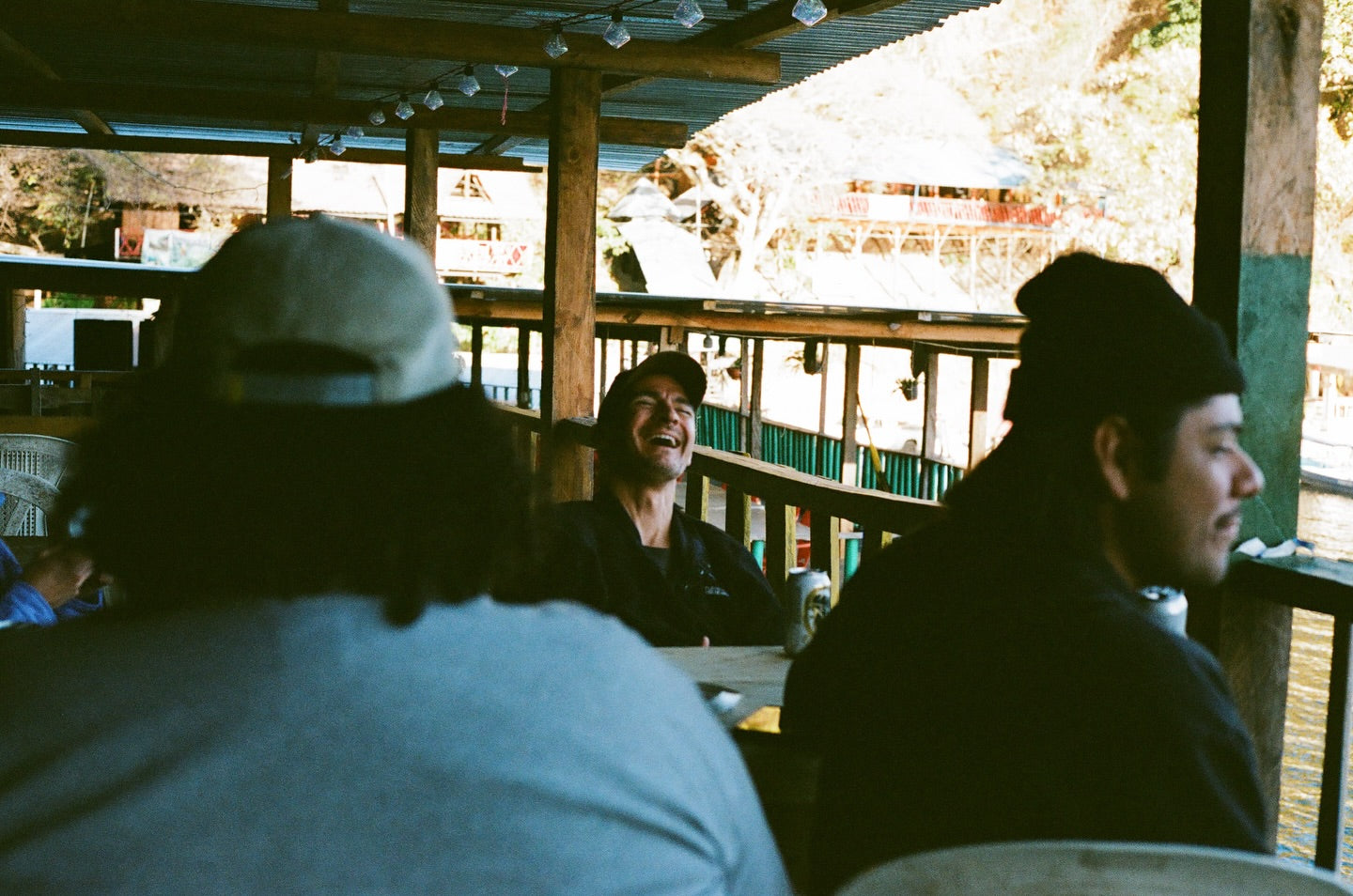 People sitting at a table on a wooden deck with a scenic background